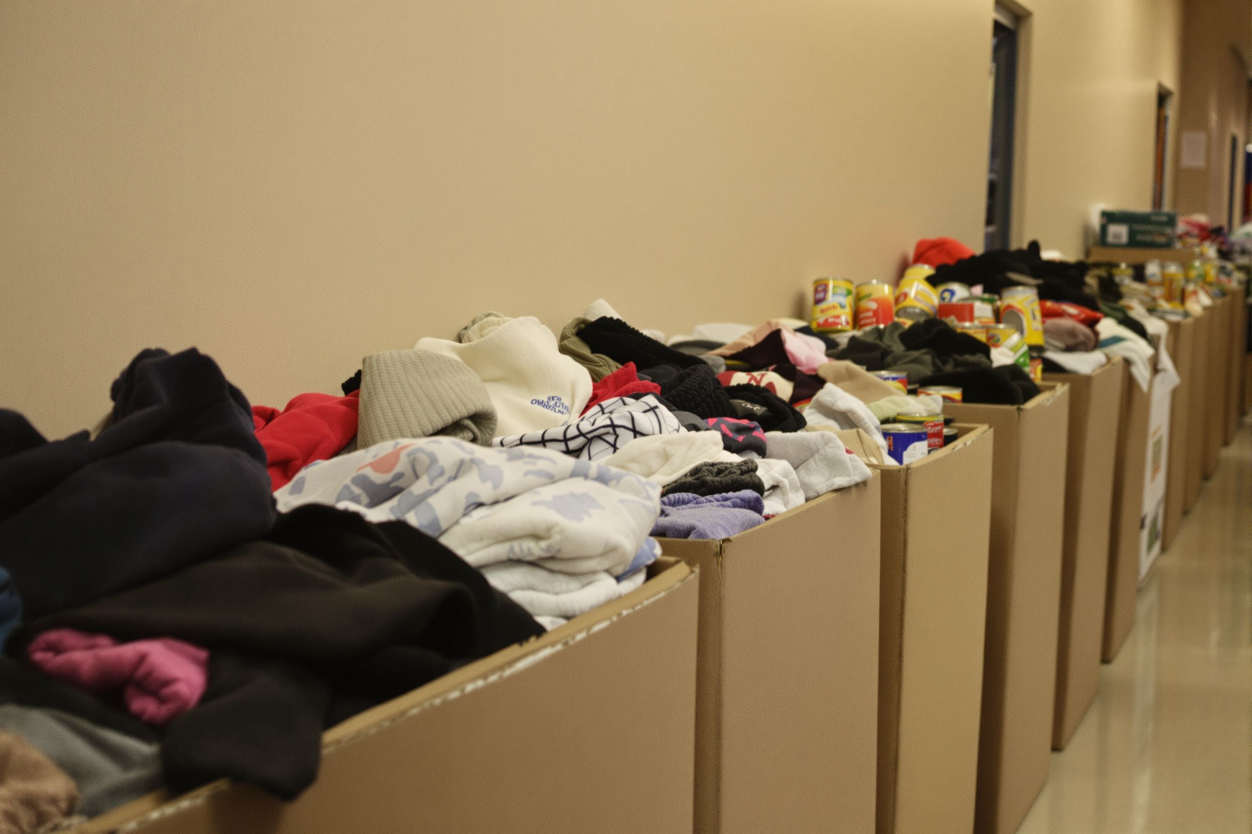 Donation boxes filled with coats, scarves and canned food along a hallway